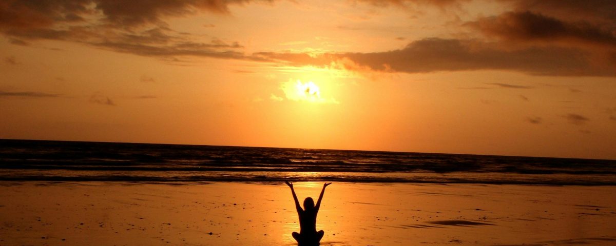 Peaceful meditation silhouette at sunset on a serene beach.